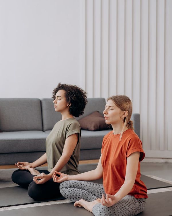 Children joyfully practicing a simple yoga pose in a bright room.